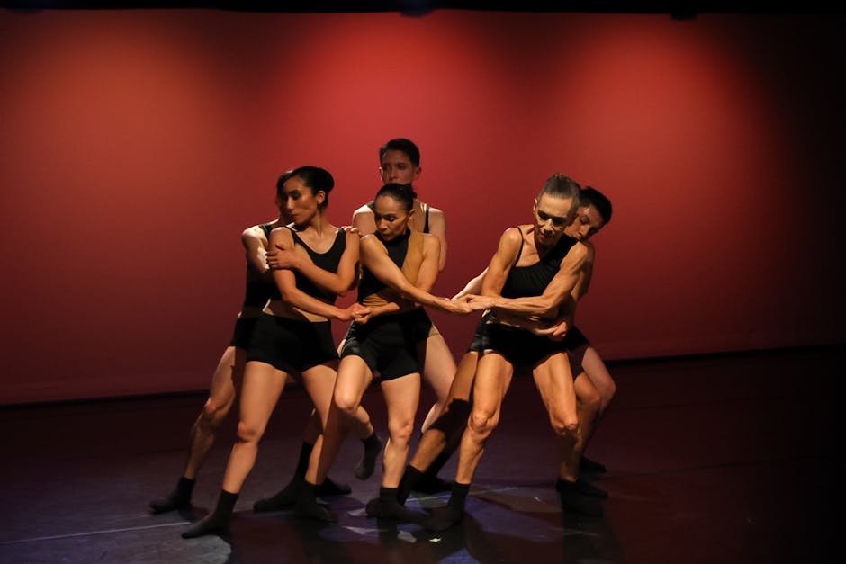 Dynamic group of dancers performing contemporary choreography under stage lights.