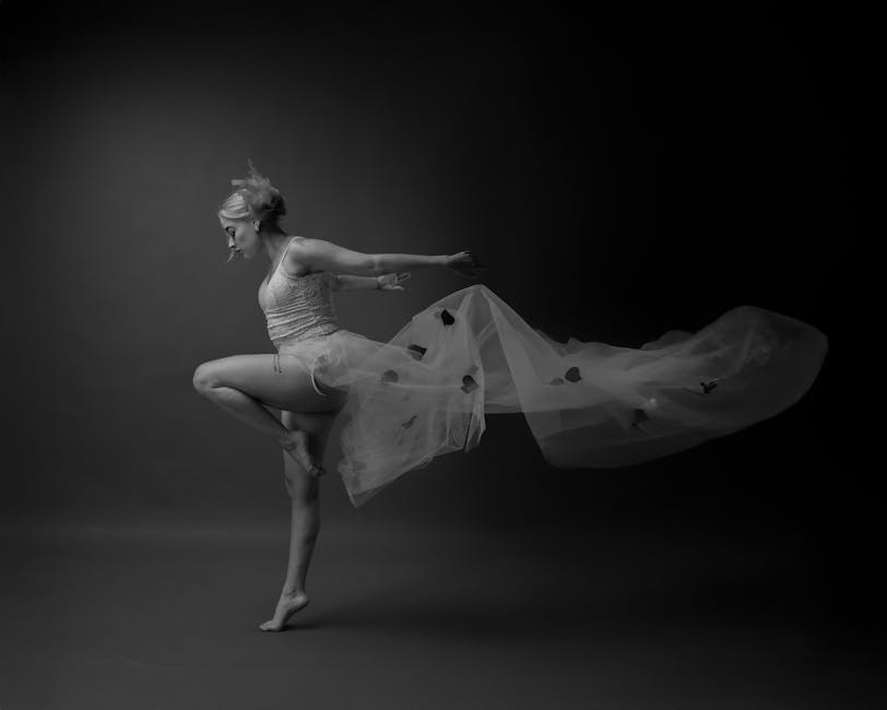 Monochrome photo of a ballet dancer in midair, draped in flowing fabric, capturing grace and motion.