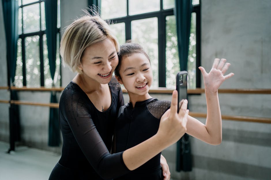 Delighted female  ballet instructor and girl trainee wearing black leotards taking selfie on mobile phone in light ballet studio